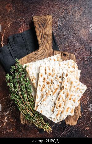 Felice concetto di Pasqua, matzah su un asse di legno. Sfondo scuro. Vista dall'alto Foto Stock