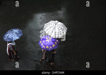 Mumbai; Maharashtra; India- Asia, giugno 2019 : immagine sfocata, vista aerea, tre Signore che camminano tenendo un ombrello sopra la sua testa in pioggia pesante Foto Stock