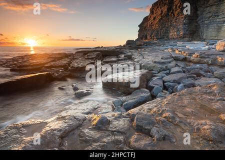 Tramonto presso la famosa spiaggia rocciosa di Ogmore-by-Sea nella vale di Glamorgan, Galles del Sud, Regno Unito mentre il sole stava tramontando Foto Stock