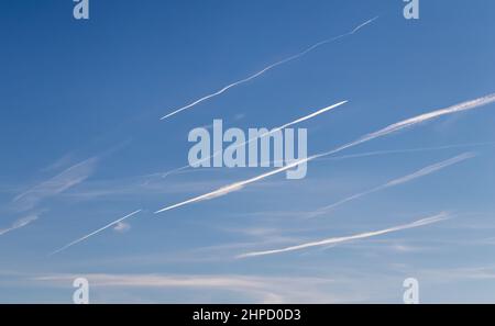 Contrails - aerei da trasporto volanti con piste di condensazione bianche nel cielo blu Foto Stock