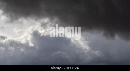 nuvole di tempesta e nuvole nel cielo parzialmente illuminate dal sole Foto Stock