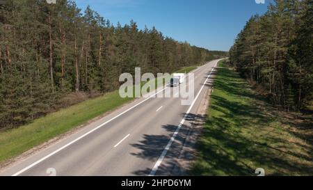 Un'auto solitaria con Camper sta guidando su una strada rurale vuota un concetto di viaggiatore unico Foto Stock