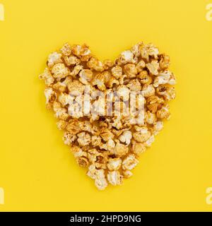 pop corn a forma di cuore in giallo, primo piano con spazio per testi, snack dolci, popcorn caramello per guardare film Foto Stock