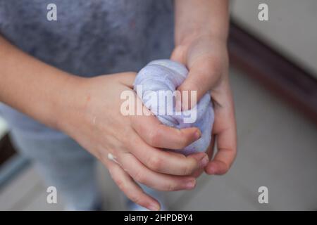 Il bambino rugge la calce nelle mani. Sostanza appiccicosa. Prodotti a base di farina con proprietà di trazione. Due mani si strinzano una cosa leggera e morbida. Foto Stock