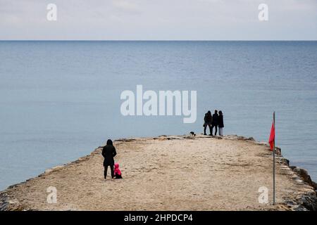 Vista ad alto angolo delle persone che si erigono su un groyne sulla riva del mare in inverno, Sanremo, Imperia, Liguria, Italia Foto Stock