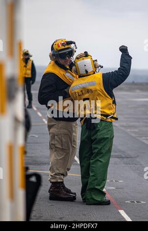 MAR DELLE FILIPPINE (Feb 17, 2022) Capo Aviation Boatswain’s Mate (Handling) Eduardo Aceves, a sinistra, da Indio, California, assegnato alla nave d’assalto anfibio dispiegata in avanti USS America (LHA 6), Parla delle fasi di lancio di un aereo da caccia F-35B Lightning II della 31st Marine Expeditionary Unit (MEU) con Aviation Boatswain’s Mate (Handling) 3rd Class Elena Gurule, di Rio Rancho, N.M., anch'esso assegnato all'America. L'America, nave principale dell'America Amphibious Ready Group, insieme al MEU 31st, opera nell'area di responsabilità della flotta USA 7th per migliorare l'interoperabilità Foto Stock