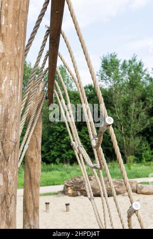 Rete di arrampicata su corda al parco giochi. Parco avventura corda. Moderno parco giochi per bambini realizzato con materiali naturali. Foto Stock