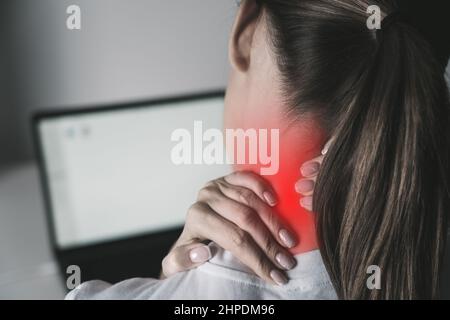 Donna che soffre di dolore al collo dopo aver lavorato sul laptop Foto Stock