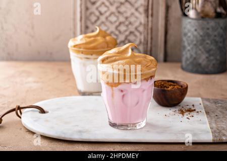 Dalgona ha montato il caffè con latte di fragola ghiacciato in un bicchiere, caffè alla moda Foto Stock