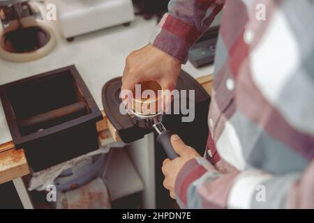 Il barista preme il caffè macinato nel portafiltro con manomissione Foto Stock
