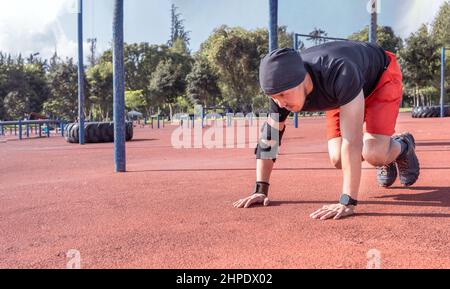 Giovane uomo che fa esercizi di riscaldamento prima della sua routine sportiva in un parco Foto Stock