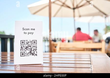 Codice QR per il pagamento senza contactless, senza contanti, posto sul tavolo di un ristorante terrazza. Immagine orizzontale con spazio di copia. Foto Stock