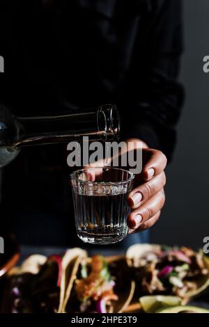 Barman mano serve mezcal messicano shot drink in un bicchiere tradizionale in Città del Messico Foto Stock