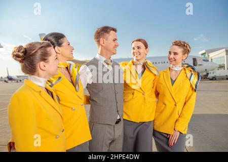 I gioiosi lavoratori di linea aerea che si levano in piedi all'aperto in campo aereo Foto Stock