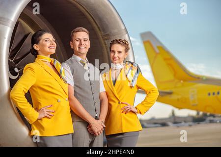 Gioiosi lavoratori aerei in piedi vicino al motore di aeromobili Foto Stock