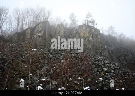 15 febbraio 2022, Hessen, Hoher Meißner: Avvolta nella nebbia è il muro di pietra di pietra dell'ex miniera di lignite a pozzo aperto di Kalbe sul versante orientale della Hohe Meißner. Un fuoco di giunco è stato bruciante qui per i secoli. Una reazione chimica fa sì che la lignite si infiammare da sola e smolga. In determinate condizioni meteorologiche, l'odore di zolfo può essere percepito a chilometri di distanza. (A dpa 'carbone incandescente nella Hohe Meißner: Fuoco di giunco è stato bruciante per secoli') Foto: Uwe Zucchi/dpa Foto Stock