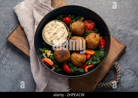 Falafel con hummus su sfondo scuro. Concetto di dieta mediterranea. Disposizione piatta, vista dall'alto Foto Stock
