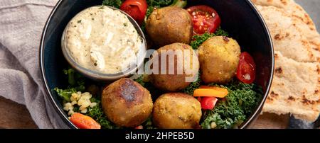 Falafel con hummus su sfondo scuro. Concetto di dieta mediterranea. Foto Stock