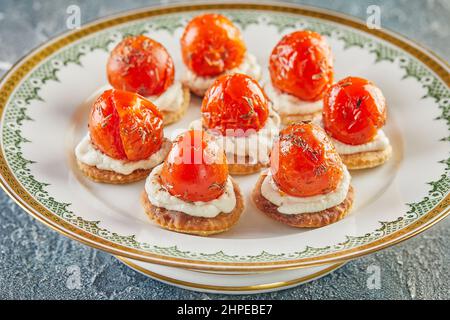 Spuntini con ricotta e pomodori ciliegini su piatto bianco d'annata. Cucina gourmet francese Foto Stock