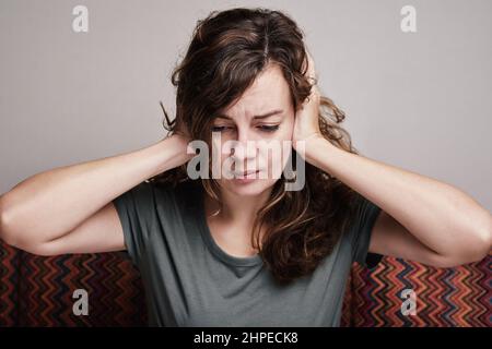 Donna coperto le sue orecchie con le mani, hanno forte mal di testa, esausta e stressata persona in depressione Foto Stock