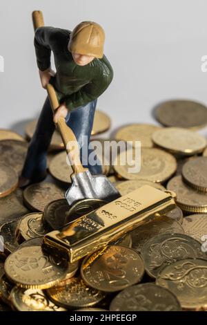 Ingegneria industriale che lavora scavando con la barra e la moneta d'oro come concetto di business e di industria. Personaggio o miniatura con monete in oro, argento, bronzo, con Foto Stock