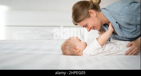 Mamma giovane e trom bambino in camera da letto, madre donna baciare il suo figlio piccolo, cura del bambino, concetto di maternità felice, banner, spazio per il testo Foto Stock