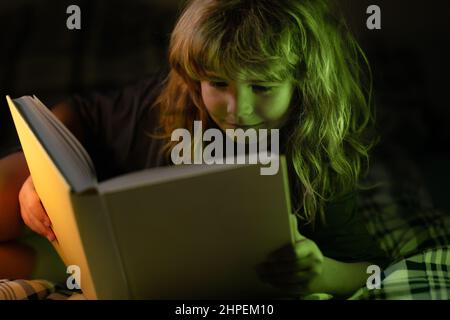 Bambino che legge un libro. I bambini dormentano, ragazzi che leggono un libro a letto. Sviluppo del bambino. Ragazzo geniale. Foto Stock