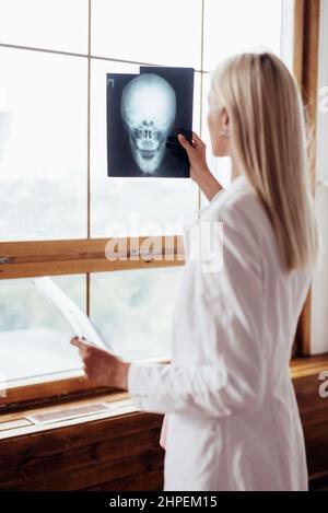Il medico tiene la radiografia della testa e la guarda alla finestra. Foto Stock
