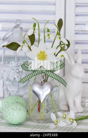 bouquet di helleborus niger e gocce di neve in bottiglia di vetro come decorazione floreale di pasqua Foto Stock