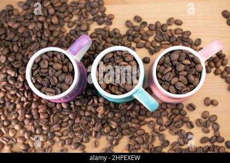 Chicchi di caffè in piccole tazze di caffè vivaci e colorate Foto Stock