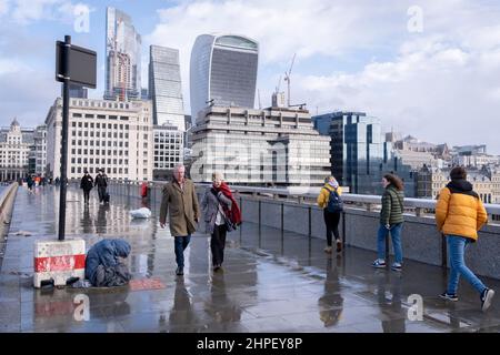 I pesestriani attraversano il London Bridge mentre la tempesta Eunice attraversa l'Inghilterra meridionale e il Galles e i venti della forza di gallina attraversano la City di Londra, il 18th febbraio 2022, a Londra, in Inghilterra. Foto Stock