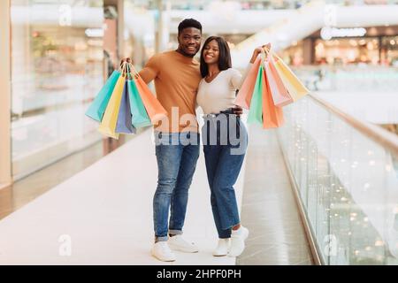 Bella coppia nera che tiene borse shopping guardando in posa alla macchina fotografica Foto Stock