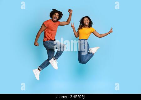 Spensierate gli amanti del nero che si divertono sullo sfondo blu dello studio Foto Stock