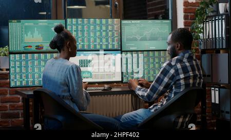Broker che fanno il lavoro di squadra per creare la crescita delle vendite di scambio di forex, utilizzando workstation multi monitor. Analizzare i numeri del mercato azionario per pianificare la strategia di investimento finanziario. Scatto su cavalletto. Foto Stock