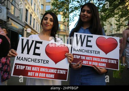Le giovani donne posano per la macchina fotografica tenendo un segno We Love Manchester in seguito al bombardamento nel 2017. Foto Stock