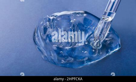 Acqua tessuto gel superficie di prodotto cosmetico per la salute della pelle. Siero di gel ialuron trasparente in pipetta su sfondo blu. Campione campione di Foto Stock