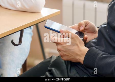 Giovane uomo che usa uno smartphone per inviare SMS e comunicare Foto Stock