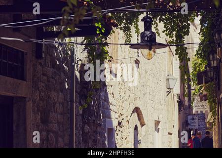 Gente nella città vecchia di Trogir, Croazia, camminando in una strada stretta che conduce ad un caffè invitante Foto Stock