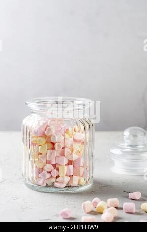 Marshmallow color pastello in vaso di vetro su sfondo grigio. Messa a fuoco selettiva. Foto Stock