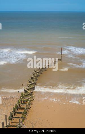 Ammira il Mare del Nord dalla cima della scogliera di Overstrand, Norfolk, Inghilterra, Regno Unito, in una giornata di sole con un groyne dogged in primo piano Foto Stock