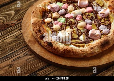 Pizza dolce intera servita con marshmallows e caramelle su sfondo di legno Foto Stock