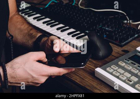 le mani del maschio caucasico usando un telefono in uno studio domestico, trasmettendo i messaggi, tecnologia e concetto di comunicazione. Foto Stock