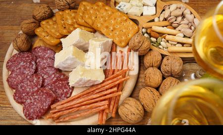 Spuntino per il vino. Piatto di formaggi e carni. Salsiccia, formaggio, noci, uva, cracker su tavola di legno. Cucina italiana per incontri o incontri romantici con gli amici Foto Stock