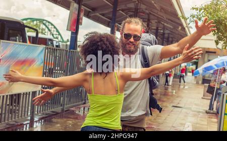 Ragazza che incontra il suo ragazzo dal suo viaggio alla stazione degli autobus Foto Stock