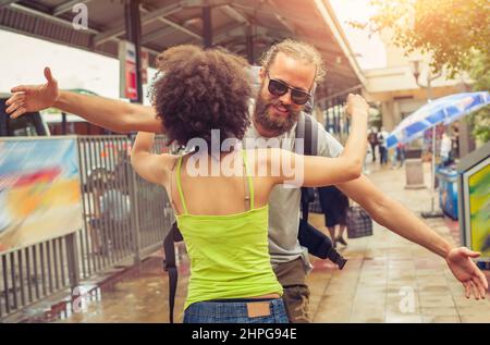 Ragazza che incontra il suo ragazzo dal suo viaggio alla stazione degli autobus Foto Stock