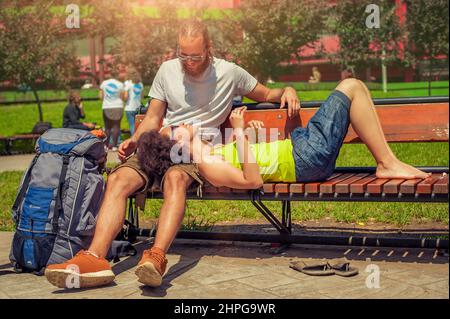 Bella coppia giovane che riposa insieme su una panca di legno nel parco Foto Stock