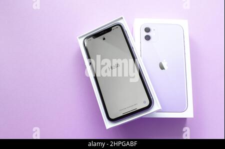 Mosca, Russia, Maggio 2021: Un nuovo iPhone 12 modello di colore viola in una scatola di marca aperta su sfondo lilla. Sullo schermo dell'iPhone, un benvenuto in Spani Foto Stock