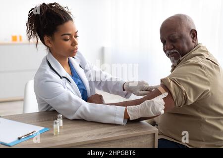 Uomo anziano vaccinato contro Covid, Dottore che applica Plaster Foto Stock