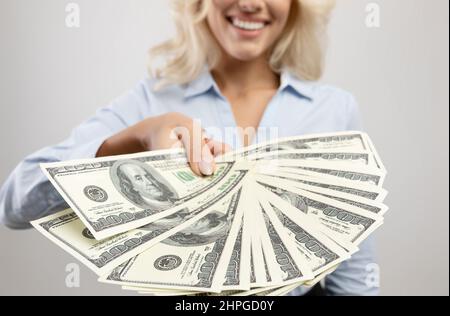 Donna d'affari irriconoscibile che tiene fan di denaro americano su sfondo studio chiaro, primo piano di mani. Vista ritagliata della signora che mostra le banconote. Fin Foto Stock