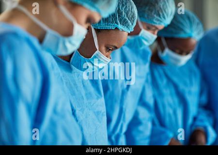 Focalizzato nel teatro operatoria. Scatto ritagliato di un gruppo di chirurghi che eseguono una procedura medica in una sala operatoria. Foto Stock